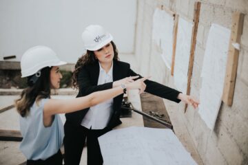design build project management process with construction manager reviewing blueprints on site