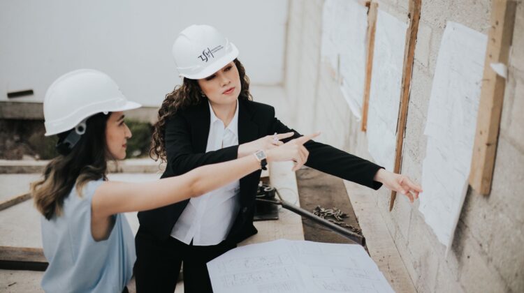 design build project management process with construction manager reviewing blueprints on site
