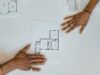 Vendor management in construction project tracking with project manager reviewing blueprints